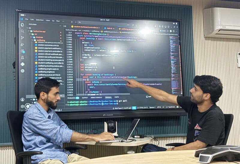 Koshur Scientist team members reviewing product code on a large display Koshur Scientist team members reviewing product code on a large display